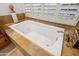 Clean white bathtub with jets and stone tile surround with privacy shutters allowing soft, natural light at 6128 E Brilliant Sky Dr, Scottsdale, AZ 85266