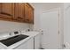 Laundry room featuring washer, dryer, wood cabinets, and access door at 6128 E Brilliant Sky Dr, Scottsdale, AZ 85266