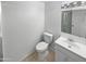 Bathroom features a white toilet, vanity, sink and faucet, and mirror, all accented by neutral tile flooring and crisp white walls at 701 W Wilshire Dr, Phoenix, AZ 85007