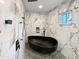 Modern bathroom with a sleek black soaking tub, marble walls, and contemporary fixtures at 701 W Wilshire Dr, Phoenix, AZ 85007