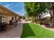 Inviting backyard with an artificial lawn, mature landscaping, and covered patio at 904 W Horseshoe Ave, Gilbert, AZ 85233