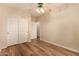 Bright bedroom showcasing a closet, ceiling fan, and neutral walls with wood-style flooring at 10339 E Juanita Ave, Mesa, AZ 85209