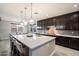 Stylish kitchen featuring an island with bar seating, dark cabinets, and modern pendant lighting at 10702 E Sheffield Dr, Mesa, AZ 85212