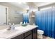 Well-lit bathroom featuring a blue shower curtain, framed mirror, and neutral walls at 10840 W Saddlehorn Rd, Peoria, AZ 85383