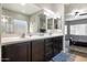 Well-lit bathroom with double vanity, dark cabinets, and a clear view into the primary bedroom at 10840 W Saddlehorn Rd, Peoria, AZ 85383