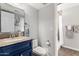 Well-lit bathroom with granite countertop vanity, blue cabinets, and adjacent shower at 12601 S Tonto Ct, Phoenix, AZ 85044