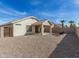 Backyard area with neutral-toned home, covered patio, fire pit, and low-maintenance landscaping at 13267 W Port Au Prince Ln, Surprise, AZ 85379