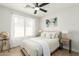 Cozy bedroom with a ceiling fan, light-colored walls, wood floors, and a large window at 13267 W Port Au Prince Ln, Surprise, AZ 85379