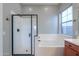 Bright bathroom featuring a glass-enclosed shower, soaking tub under a window, and neutral color palette at 139 E Desert Broom Dr, Chandler, AZ 85286