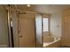 Bright bathroom with a glass-enclosed shower and a soaking tub surrounded by tiled walls and a glass block window at 14334 W Avalon Dr, Goodyear, AZ 85395