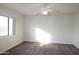 Bright bedroom features a ceiling fan, neutral carpet, and a large window with natural light at 14334 W Avalon Dr, Goodyear, AZ 85395