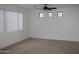 An empty living room with neutral walls, large window and ceiling fan ready for its new owner's personal touch at 14334 W Avalon Dr, Goodyear, AZ 85395