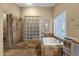 This elegant bathroom includes a glass shower, separate tub and travertine tile at 15011 N 45Th Pl, Phoenix, AZ 85032