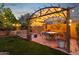 Backyard view featuring an outdoor seating area with overhead lighting, potted plants, and lush landscaping at 15011 N 45Th Pl, Phoenix, AZ 85032