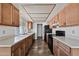 Long, galley-style kitchen with tile floors, black appliances, and wood cabinets at 15652 N 52Nd St, Scottsdale, AZ 85254