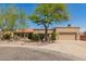 Tan home with a desert landscape, mature tree, and a spacious driveway leading to a two-car garage at 15843 E Mustang Dr, Fountain Hills, AZ 85268