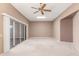 Spacious living room with neutral carpet, ceiling fan, and sliding glass door at 17247 N 106Th Ave, Sun City, AZ 85373