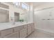 Bright bathroom featuring dual sinks, a glass shower enclosure, and a large mirror with vanity lighting at 22120 N Old Mine Rd, Sun City West, AZ 85375