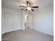 Neutral carpeted bedroom with a ceiling fan, closet, and doorway that lead to a private bathroom at 2260 S Deerfield Ln, Gilbert, AZ 85295