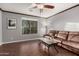 Cozy living room with wood floors, leather sofa, ceiling fan, and a large window for natural light at 28735 N 21St Ave, Phoenix, AZ 85085