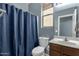 Well-lit bathroom with a shower curtain, toilet, and wooden vanity with sink at 3238 W White Canyon Rd, San Tan Valley, AZ 85144