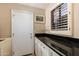 Bright laundry room features a large black countertop, storage cabinets, and window with shutter at 33389 N 71St St, Scottsdale, AZ 85262