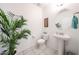 Stylish powder room featuring a pedestal sink, tile floors, and a decorative palm tree at 3482 N 300Th Dr, Buckeye, AZ 85396