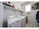 Functional laundry room features a modern washer and dryer, shelving, and a window for natural light at 3482 N 300Th Dr, Buckeye, AZ 85396