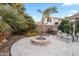 Inviting backyard with a stylish stone fire pit, palm trees, and patio seating under a clear blue sky at 4272 E Ivanhoe St, Gilbert, AZ 85295