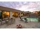 Sparkling pool with a waterfall feature, a spa, patio seating, and desert landscaping during a brilliant sunset at 4272 E Ivanhoe St, Gilbert, AZ 85295