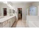 Bathroom featuring dual sinks with white cabinetry, walk in closet, tub and glass shower at 4272 E Ivanhoe St, Gilbert, AZ 85295