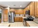 Spacious kitchen featuring oak cabinets, tiled countertops, stainless steel refrigerator, and modern appliances at 4272 E Ivanhoe St, Gilbert, AZ 85295