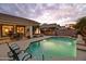 Backyard pool with waterfall, spa, patio, lion statue and view of the desert landscaping at dusk at 4272 E Ivanhoe St, Gilbert, AZ 85295