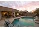 Gorgeous pool with a waterfall feature, patio seating, a spa, and lovely desert landscaping at sunset at 4272 E Ivanhoe St, Gilbert, AZ 85295