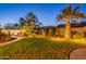 Beautiful backyard at twilight features green grass, mature palm trees, and a unique stone-lined waterfall feature at 4756 W Nogales Way, Eloy, AZ 85131