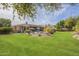 Sprawling backyard featuring mature landscaping, pool, patio, and lush green lawn at 4915 N Greentree Dr, Litchfield Park, AZ 85340