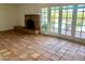 Cozy living room with terracotta tile flooring and a red brick fireplace, complemented by natural light from the french doors at 537 N Jay St, Chandler, AZ 85225