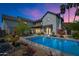 Stunning backyard at dusk with a sparkling pool, fountain, and a cozy swing, ideal for relaxation at 5601 E Monterosa St, Phoenix, AZ 85018