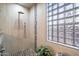 Modern shower with pebble flooring, a rainfall shower head, and a unique glass block window at 7161 W Saddlehorn Rd, Peoria, AZ 85383