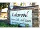 A stone sign for Oakwood Country Club & Golf Course with well-manicured foliage in front, welcoming visitors at 9638 E Tranquility Way, Sun Lakes, AZ 85248