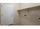 Functional laundry room with a utility sink, storage shelf, and tile floors at 1170 S Agnes Ln, Gilbert, AZ 85296