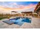 Backyard pool with a built-in hot tub, and an outdoor kitchen under the pergola. This space is for entertainment at 13018 S 177Th Ln, Goodyear, AZ 85338