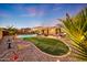 Spacious backyard with a pristine pool, firepit, outdoor kitchen, and lush landscaping, perfect for entertaining and relaxation at 18143 W Buckhorn Dr, Goodyear, AZ 85338