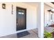 Close up of modern black front door with welcome mat and white brick facade at 3345 E Edgewood Ave, Mesa, AZ 85204