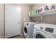 Functional laundry room with appliances, storage shelves, a door to the exterior and neutral walls at 41655 W Somerset Dr, Maricopa, AZ 85138