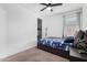 Minimalist bedroom with a dark bed frame, ceiling fan, and natural light at 4402 W Bush Bean Way, San Tan Valley, AZ 85144