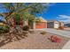 Single-story home featuring desert landscaping, a red garage door, and a tree providing shade to the house at 4402 W Bush Bean Way, San Tan Valley, AZ 85144
