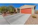Single-story home with desert landscaping, a red garage door, and a long concrete driveway at 4402 W Bush Bean Way, San Tan Valley, AZ 85144