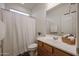 Well-lit bathroom featuring wood cabinets, a vanity, a toilet, and a shower with a curtain at 4609 S 122Nd S Dr, Avondale, AZ 85323