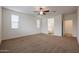 Bright main bedroom with two windows, ceiling fan, and an ensuite bathroom entrance at 4609 S 122Nd S Dr, Avondale, AZ 85323